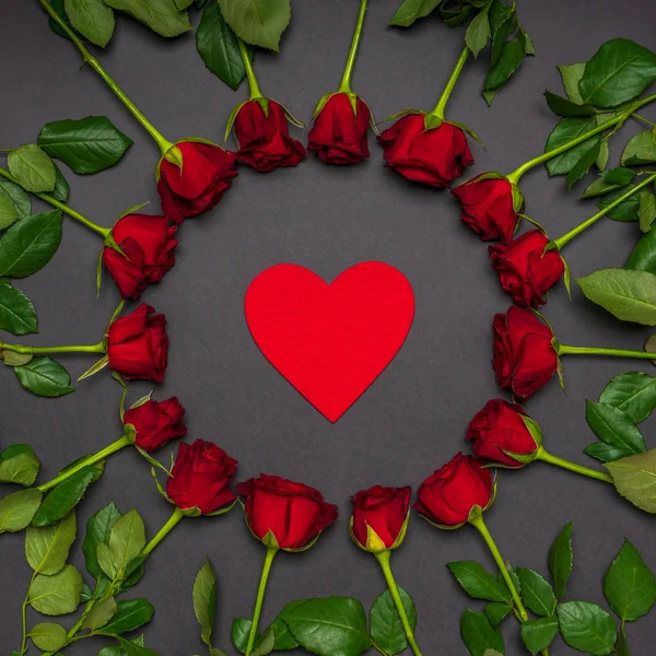 Червоне серце в круглій рамі зроблене з свіжих троянд на чорному тлі. Сучасний стиль, творча композиція. Любов, романтика, денна концепція Валентина. Вигляд зверху. — стокове фото