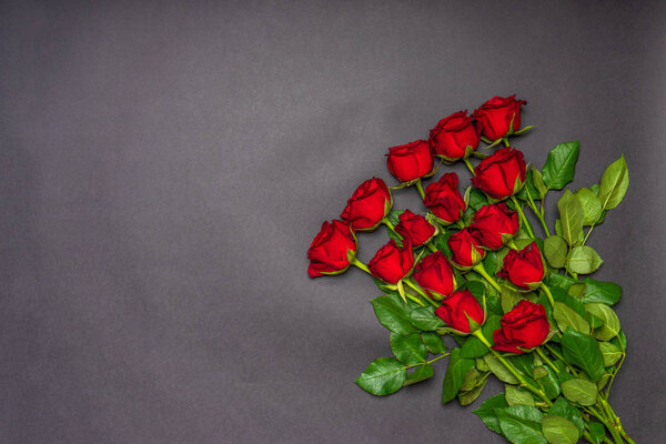 Bouquet of fresh red rose flowers on black background. Floral composition, greeting card for holiday event. Love, romance or Valentine's day concept. Flat lay, top view, mock up