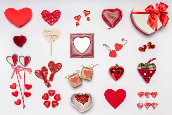 Verschiedene Herzen und stilvolle Accessoires in Herzform, Geschenke und Süßigkeiten in roter Farbe auf weißem Hintergrund. Leerer Fotorahmen, Attrappe auf. Grußkarte zum Valentinstag, Liebes- und Romantikkonzept — Stockfoto