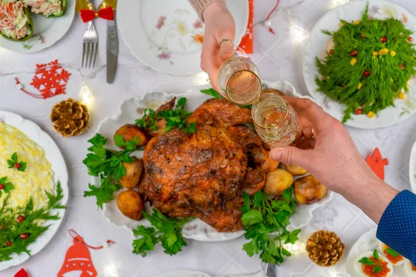 Menschenhände halten Gläser mit Sekt in der Hand. Freunde oder Familie stoßen mit Champagner auf die festliche Weihnachtstafel an. Weihnachtsessen, leckeres Essen, Winterurlaubsfeier zu Hause — Stockfoto