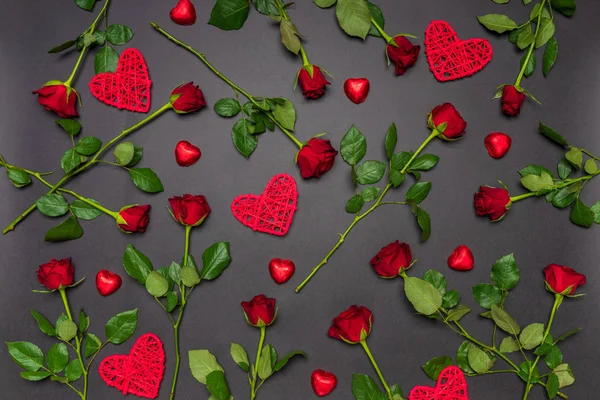 Frische Rosenblüten, dekorative Herzen und Süßigkeiten in roter Farbe auf schwarzem Hintergrund. Moderner Stil, kreative Komposition. Liebe, Romantik, Valentinstag-Konzept. Flache Lage, Draufsicht — Stockfoto