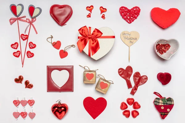 Verschiedene Herzen und stilvolle Accessoires in Herzform, Geschenke und Süßigkeiten in roter Farbe auf weißem Hintergrund. Leerer Fotorahmen, Attrappe auf. Grußkarte zum Valentinstag, Liebes- und Romantikkonzept — Stockfoto