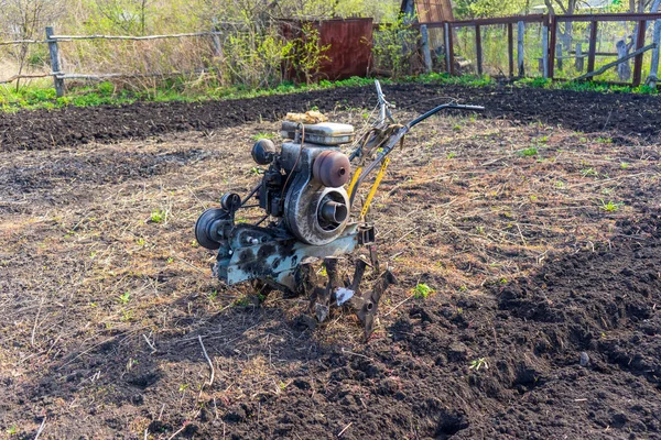 Old vintage dirty motor cultivator on suburban plot. Ploughing ground, land cultivation, soil tillage. Spring work in the garden. Gardening concept — Stock Photo, Image