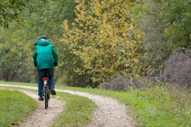 Bir orman yolu üzerinde Bisiklete binmek adam