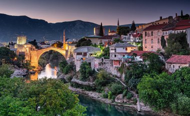 MOSTAR, BOSNIA HERCEGOVINA: 11 Ağustos 2019 'da Mostar' ın ortaçağ köprüsü üzerinde renkli günbatımı.