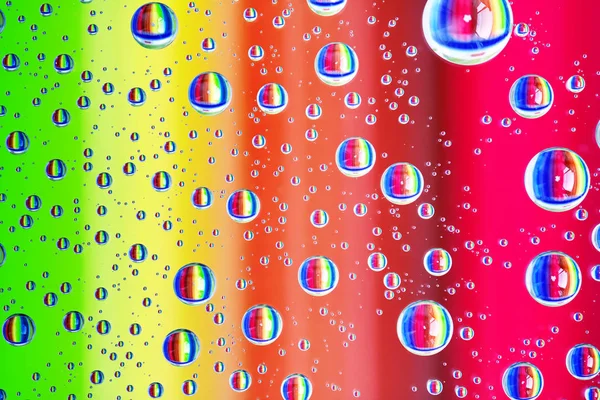 Bunte abstrakte Hintergrund von Wassertropfen auf Glas mit Regenbogenfarben — Stockfoto