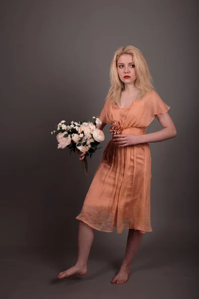 Living doll girl with flowers on a gray background