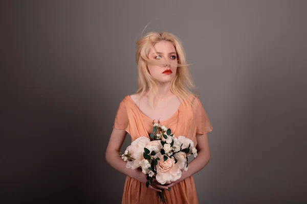 Living doll girl with flowers on a gray background