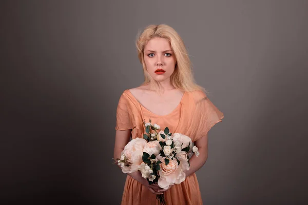 Living doll girl with flowers on a gray background