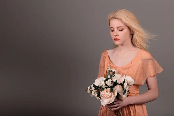 Living doll girl with flowers on a gray background