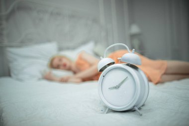 Yorgun kız yatmak istiyor ve alarm ayarlar.