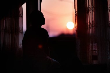 Dreaming kız pencere yakınında oturan kırmızı şafak karşılar.