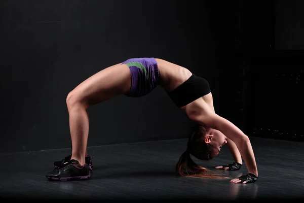 Sport fille faire de l'exercice sur un fond noir . — Photo