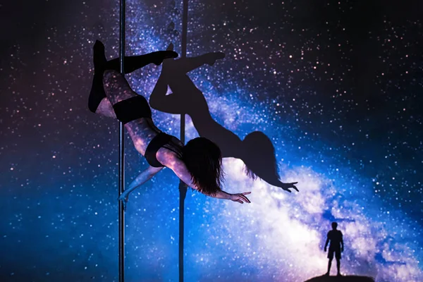 Das Mädchen auf dem Pylon macht die Übung vor dem Hintergrund der Galaxie. — Stockfoto