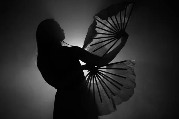 Schöne Silhouette eines Mädchens, das elegant in Rauch und Nebel tanzt. — Stockfoto