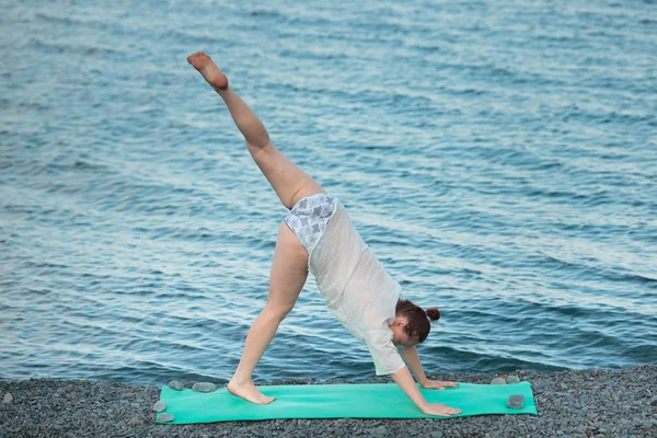 Девушка занимается йогой на берегу моря. Практика йоги в море . — стоковое фото