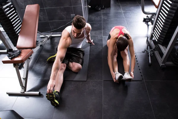A young couple stretching in the gym — Stock Photo, Image