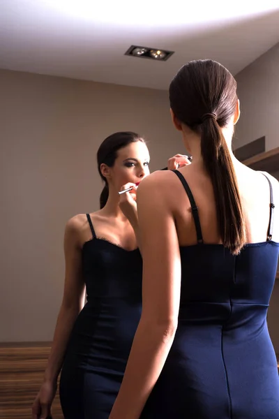 Jovem mulher vestindo batom na frente de um espelho — Fotografia de Stock