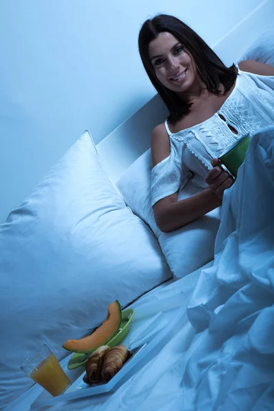 Beautiful young woman having her first coffee in bed — Stock Photo, Image