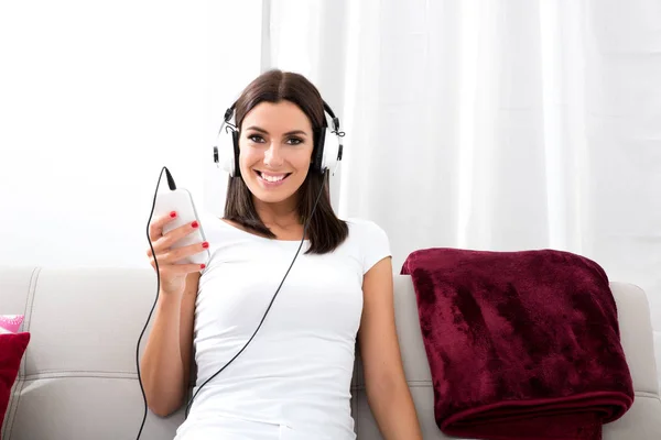 Beautiful young woman in headphones listening to music — Stock Photo, Image