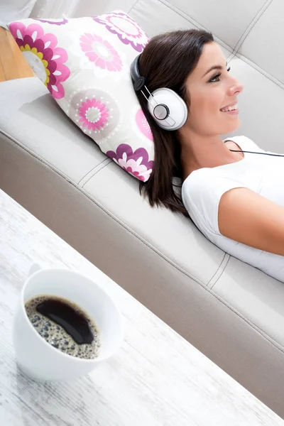 Gyönyörű fiatal nő fektetése a kanapéra, zenehallgatás — Stock Fotó