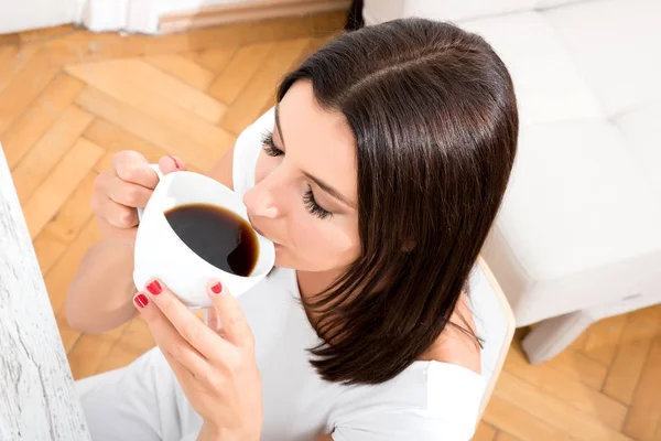 Vacker kvinna dricker kaffe hemma — Stockfoto