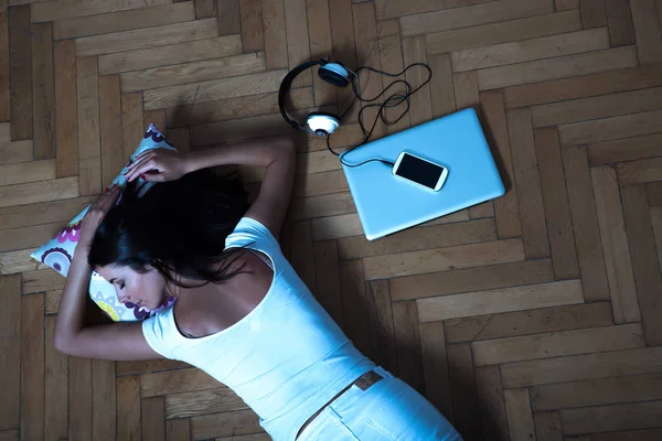 Женщина лежит на полу с ноутбуком, смартфоном, — стоковое фото