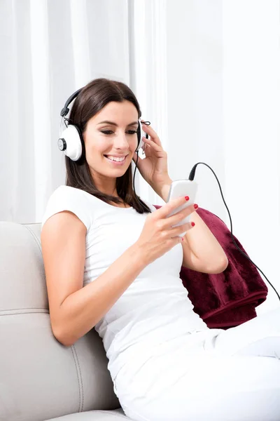 Mooie jonge vrouw in koptelefoon luisteren naar muziek — Stockfoto