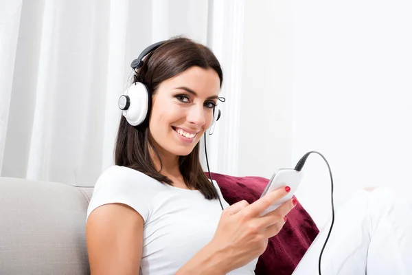 Vacker ung kvinna i hörlurar lyssnar på musik — Stockfoto