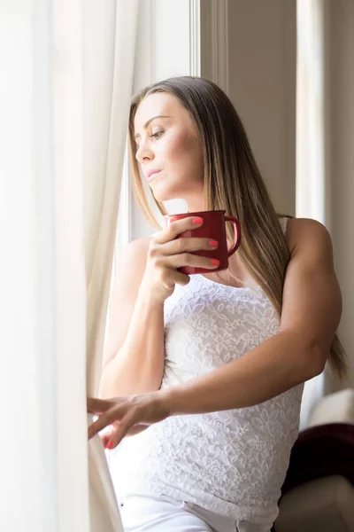 Mooie vrouw kijken uit het raam — Stockfoto