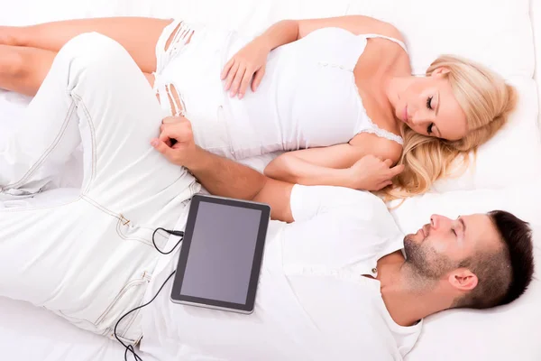 Красивая молодая пара с помощью планшетного ПК в постели — стоковое фото