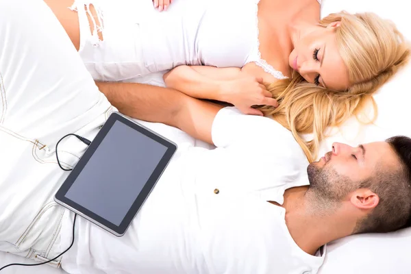 Красивая молодая пара с помощью планшетного ПК в постели — стоковое фото