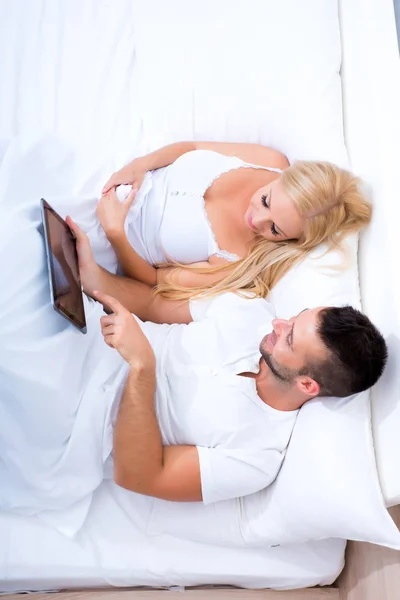 A tábla-Pc használata az ágyban a gyönyörű fiatal pár — Stock Fotó