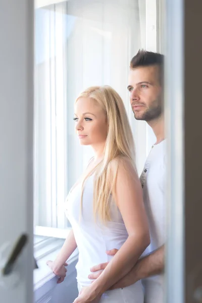 Красивая молодая пара стоя у окна — стоковое фото