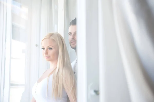 美丽的年轻夫妇站在窗口 — 图库照片