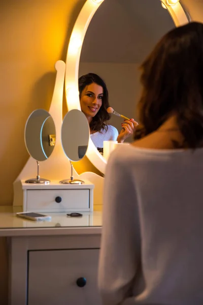 Een mooie jonge vrouw aan een tafel met make-up — Stockfoto