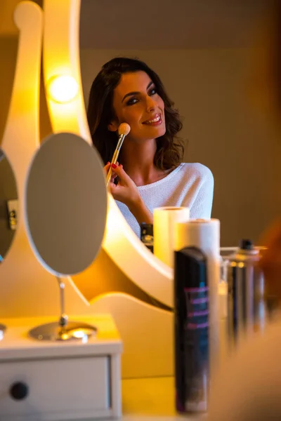 Uma bela jovem mulher em uma mesa de maquiagem — Fotografia de Stock