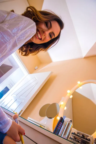 Een mooie jonge vrouw aan een tafel met make-up — Stockfoto