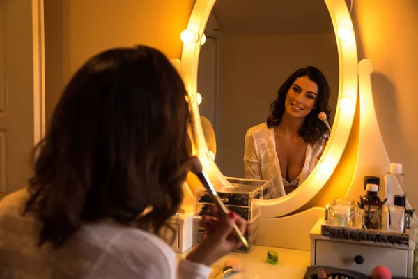 Uma bela jovem mulher em uma mesa de maquiagem — Fotografia de Stock