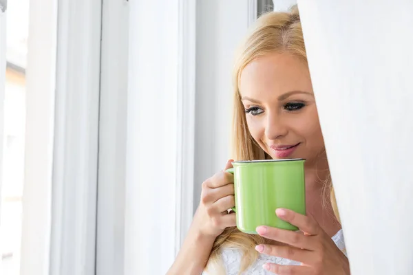 Een mooie jonge vrouw in het venster — Stockfoto