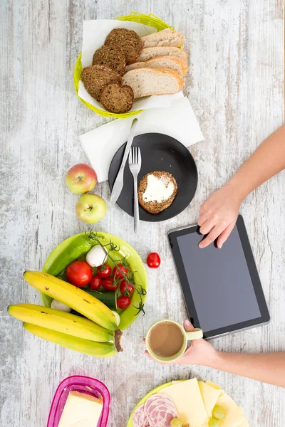 A mão de uma mulher com comida e tablet — Fotografia de Stock