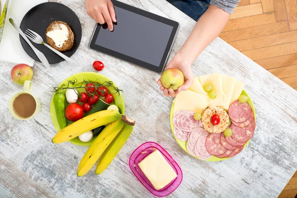 Bir kadın eli ile gıda ve tablet — Stok fotoğraf