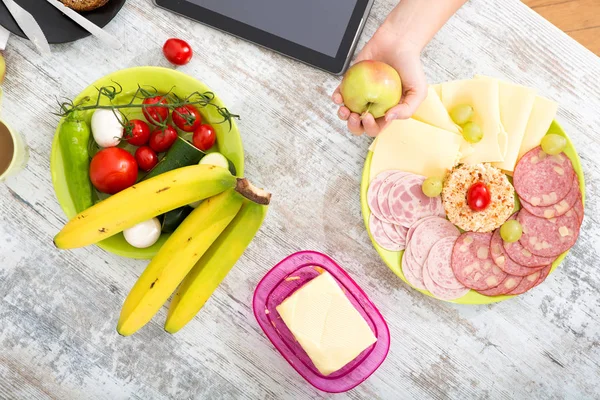 A woman's hand with food and tablet — Stock Photo, Image