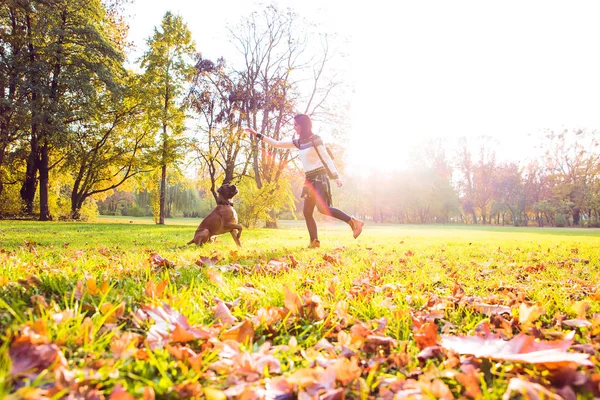 Hermosa joven jugando con su perro en el bosque — Foto de Stock