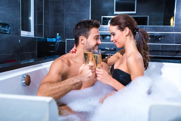 Beautiful young couple drinking Champagne in the Whirlpool