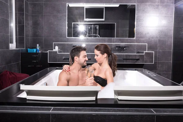 Bella giovane coppia che beve Champagne nella vasca idromassaggio — Foto Stock