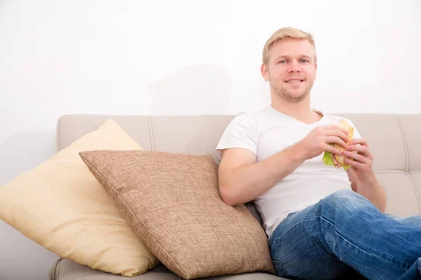 Ung man äter en smörgås hemma — Stockfoto