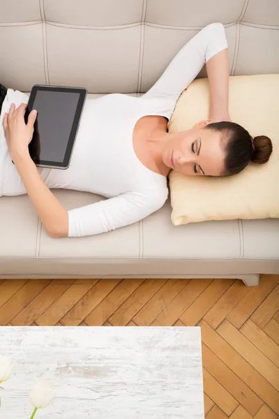 Giovane donna con un Tablet PC sul divano — Foto Stock