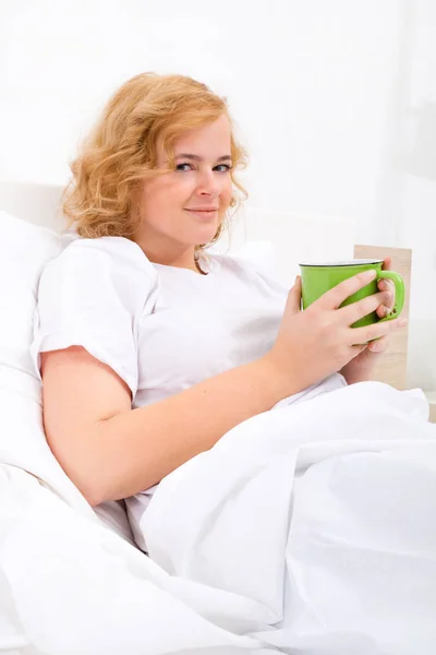 Молодая женщина пьет кофе в постели — стоковое фото