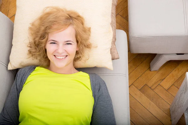 A young smiling woman relaxing on the sofa. — Fotografia de Stock